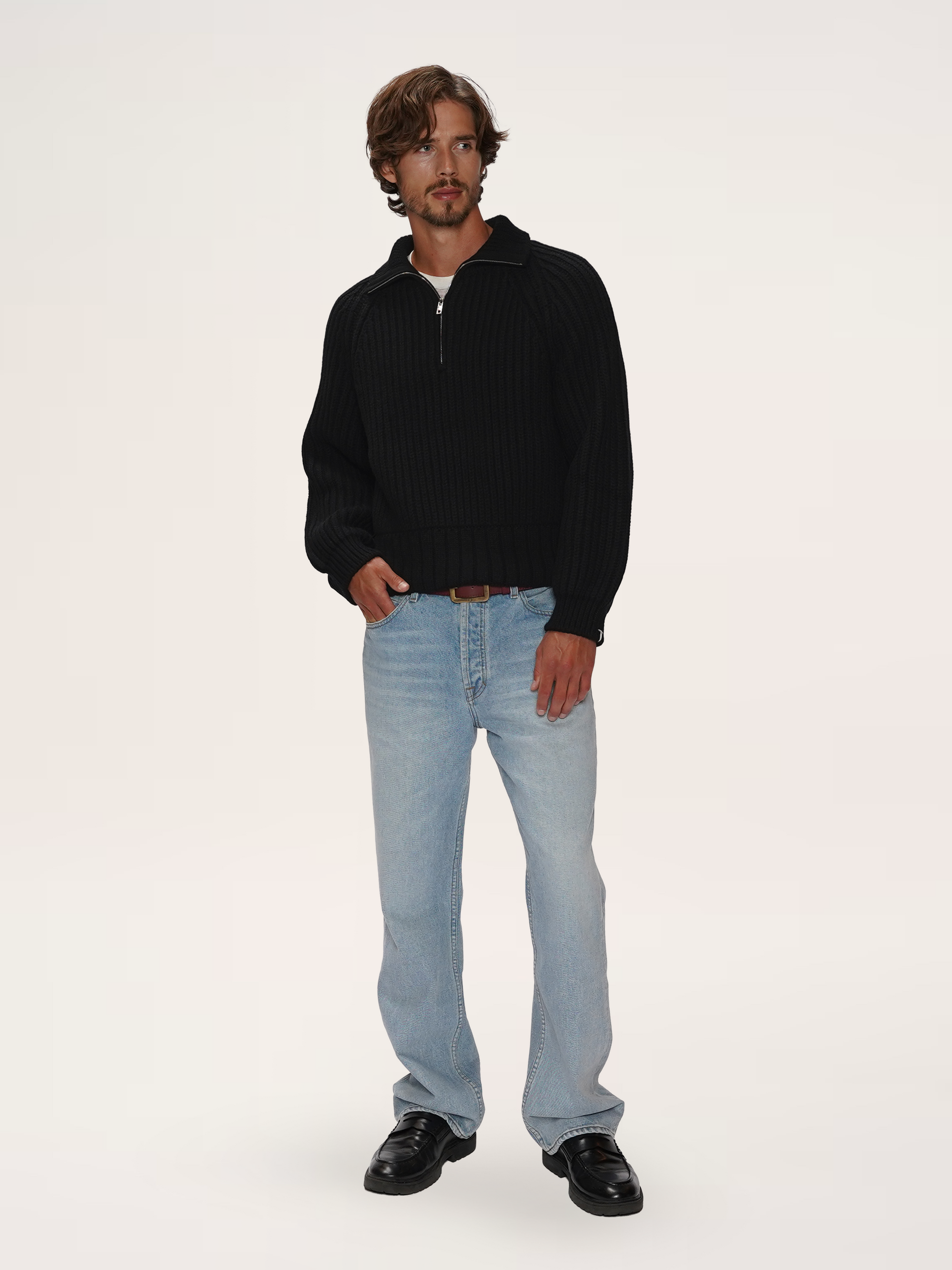 Male model wearing a TENDLER black heavyweight recycled cashmere half-zip sweater with light wash straight-leg jeans.