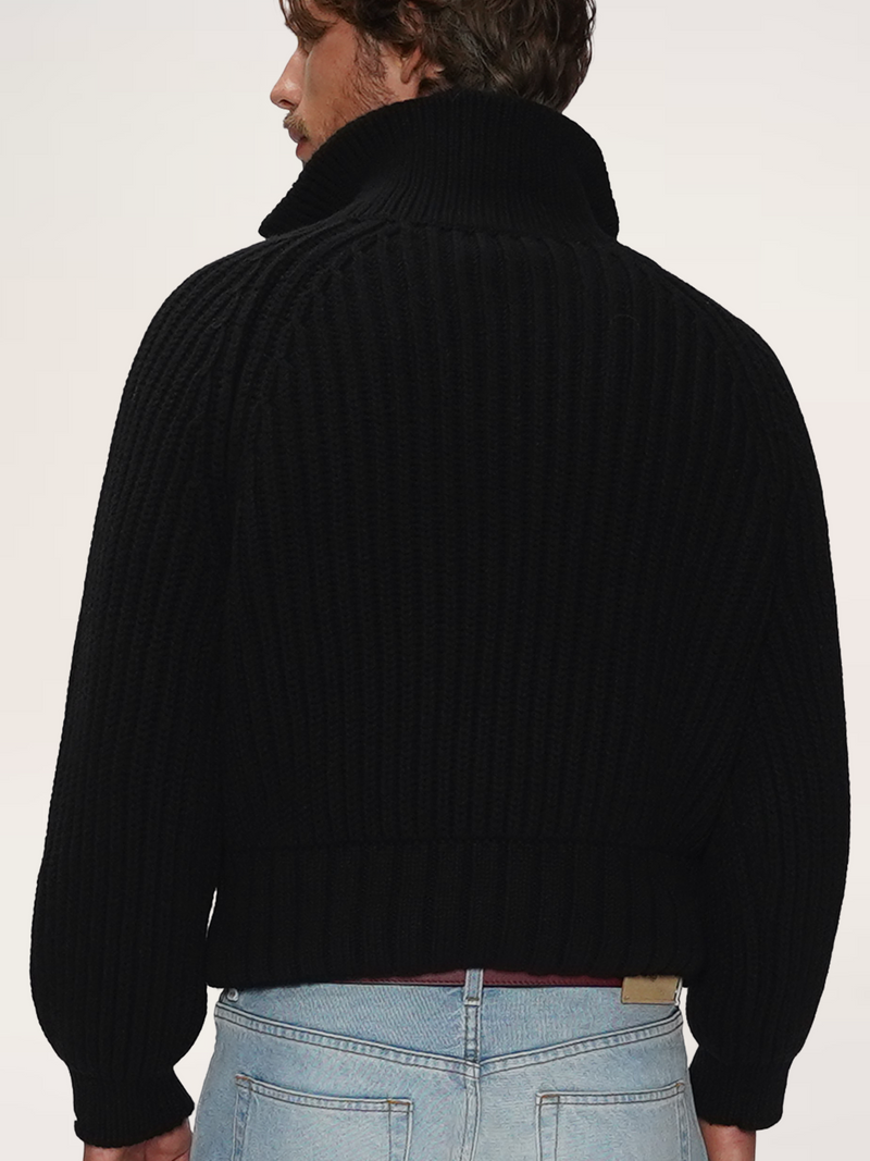 Rear view of a male model wearing a TENDLER black heavyweight half-zip knit sweater with a high ribbed collar. 