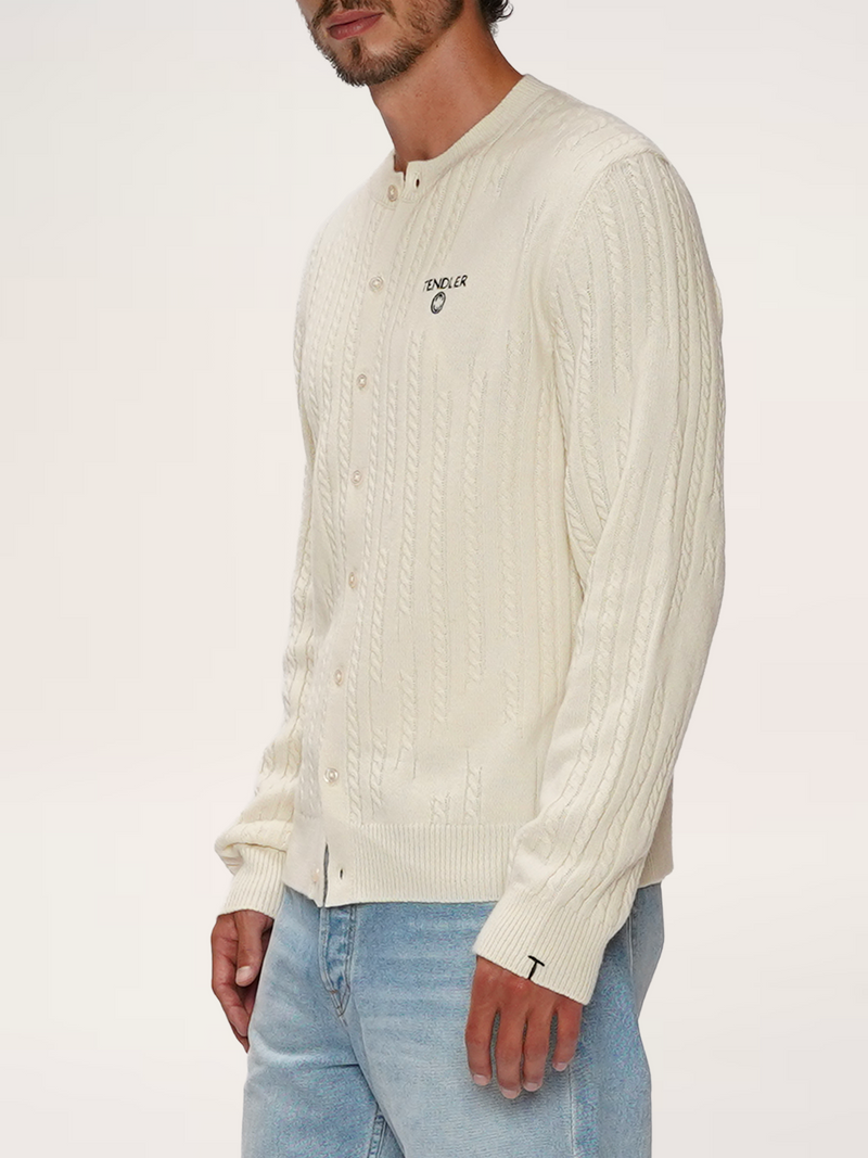 Three-quarter side shot of male model in TENDLER cream ivory crewneck cardigan on a model, showing the embroidered logo and cable knit sleeve.